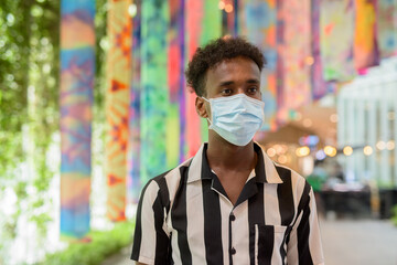 Portrait of handsome black African man wearing face mask in shopping mall