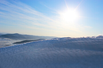 Winter landscape. Snowdrift against the background of mountains and blue sky and shining sun