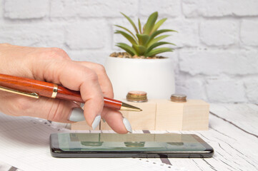 Female accountant uses mobile phone with pen to calculate profit and loss, business concept, office background