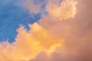 Beautiful cloudscape - pink-orange clouds in the rays of the sun against the blue sky