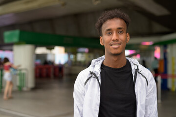 Portrait of handsome black African man smiling at train station
