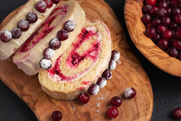 Homemade biscuit sweet roll with cranberries and cream on a black table, top view, flat lay