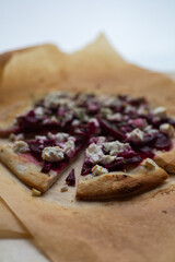 Vegetarian pizza. Homemade pizza with beets and feta cheese, garnished with arugula microgreens. Healthy fast food pizza on baking paper background. Selective focus.