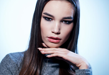 Beautiful brunette model in gray sweater with makeup cropped view on light background