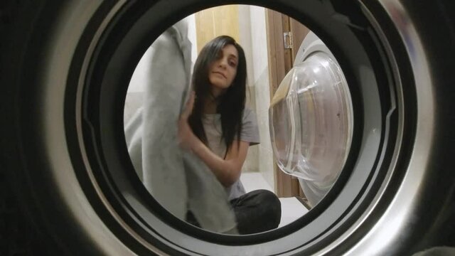 Attractive woman load washing machine with clothes to wash