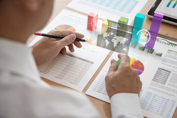Business man interacting touching on a futuristic augmented reality screen while analysing or reviewing on business performace and investment analysis or return on investment, ROI.