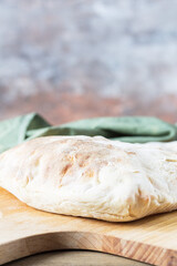 A homemade white puffy tortilla sits on a wooden bread shovel against a blurry background. Bread with flour sourdough.