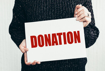 Girl holding a card with text DONATION.
