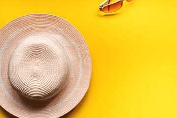 Pretty straw hat and pink sunglasses for outdoor.On yellow background