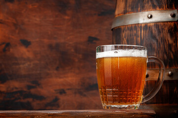Mug of light lager beer and old wooden barrel