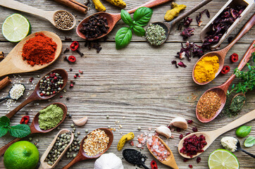 A selection of various colorful spices on a wooden table in  spoons