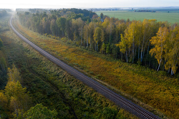 Fototapeta na wymiar aerial view of railroad in forest at foggy autumn morning