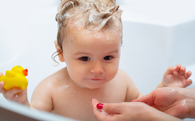 Child bathing. Baby showering. Portrait of kid bathing in a bath with foam.