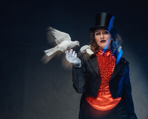 Spectacular female conjurer in dark background with spotlight and doves