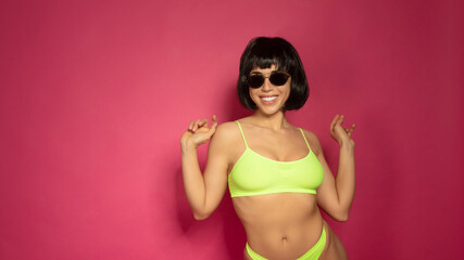 Obraz premium Cute smiling brunette woman in yellow lingerie on pink background.