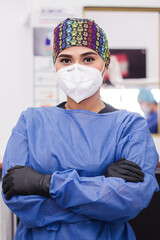 A portrait of a female dentist in her clinic with safety clothing and mask. Retrato de una dentista...