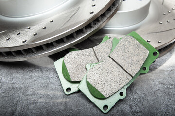 brake pads and perforated brake discs on a stone gray table