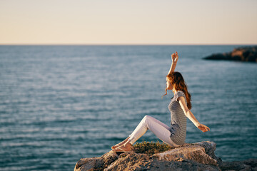 woman in a striped T-shirt raised her hands up near the sea in peas