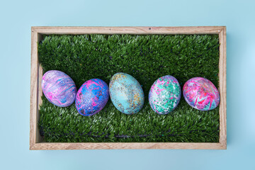 Colorful painted eggs with bright shiny gliter in wooden box