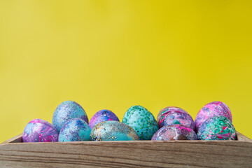Colorful painted eggs with bright shiny gliter in wooden box