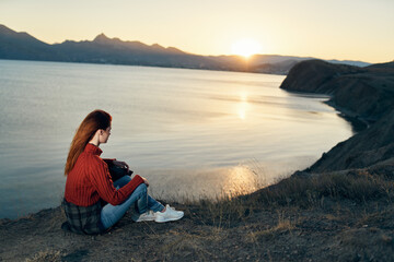 woman sits on the ground in nature in the mountains near the sea adventure sunset