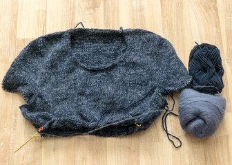 knitted gray-blue sweater, wooden knitting needles and yarn balls, knitting hobby, handmade