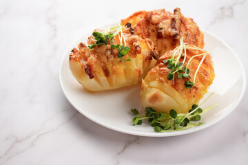 Classic baked potatoes with cheese and bacon topped with microgreens in white plate on the table. Healthy homemade food concept. Selective focus