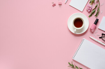 Workplace with notepad, pen, coffee cup and other accessories on pink background