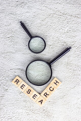 Black magnifying glass with research text on light gray background. Statistic analyzing and...