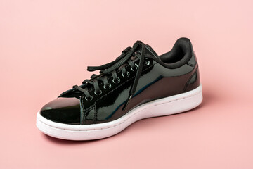 patent leather black color sneakers isolated on pink background Top view flat lay Casual wear