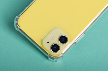 Yellow iPhone 11 close up in clear silicone case back view isolated on green background, phone case...