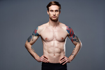 Fototapeta premium sporty man tattoos on his arms naked torso bodybuilder gray background