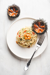 Pasta spaghetti with sea urchins (ricci di mare) in the white plate on the white wooden background....