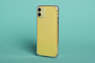 Phone case mock up side view. Yellow iPhone 11 in clear silicone case isolated on green background