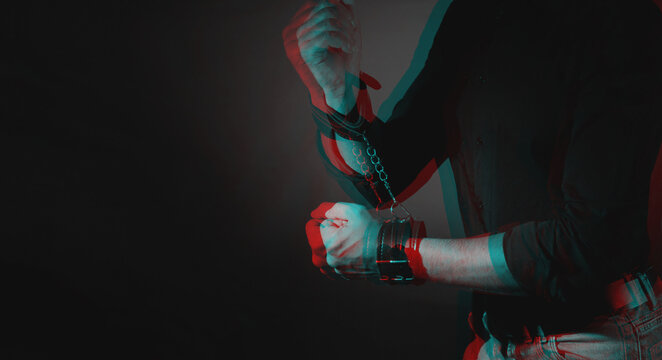 A man hands wearing a pair of black furry leather sex toy handcuffs for sex. Black and white with 3D glitch virtual reality effect