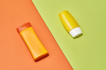 Plastic orange and yellow tubes, bottles with natural vitamin C body care product isolated over creative orange and green background
