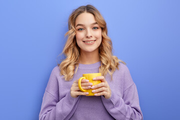 cute positive girl drinking coffee or tea in morning before school or university