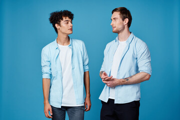 guys in identical shirts and a t-shirt on a blue background friends gesticulate with their hands