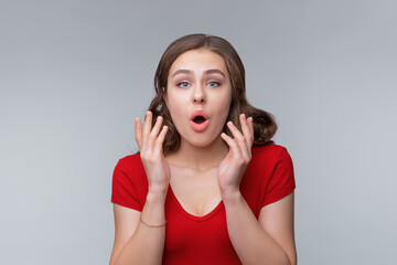 Fototapeta premium Surprised young brunette woman stare fascinated with opened mouth with disbelief at lucky good news, gasping impressed