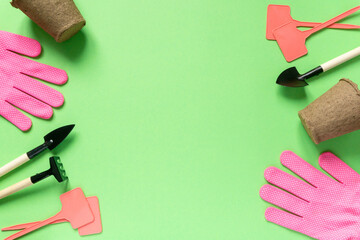 Flat lay of gardening supplies. Tools, peat pots, gloves and seedling plates on green background,...