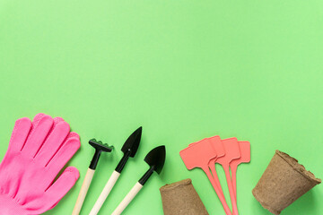 Set of gardening supplies. Tools, peat pots, gloves and seedling plates on green background, space...