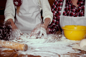 Mom teaches her daughter to knead the dough. Adult and little girls. Beautiful wooden background....