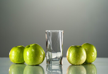 Green apples are on the table. next to it is an empty glass for apple juice. Hard apple cider cocktail with fall cinnamon, cardamom and star anise