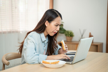 Asian beautiful girl feeling hungry while working on computer at home.