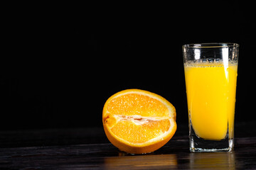A ripe sliced orange and a tall glass of juice on a wooden background. close-up. healthy lifestyle. healthy eating. vitamins. Summer mood. For design sign