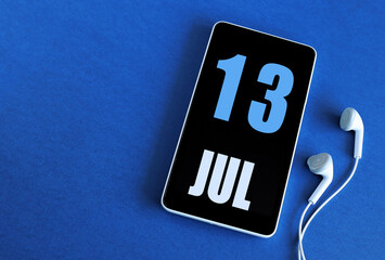July 13. 13 st day of the month, calendar date. Smartphone and white headphones on a blue background. Place for your text. Summer month, day of the year concept