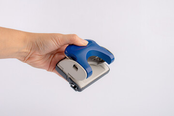 Hand holding office puncher isolated on white background