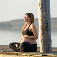 Pregnant woman sitting on a jetty while enjoying the sun