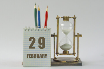 Day of month.Calendar,sand in vintage hourglass, colored pencils, notepad,procrastination and...