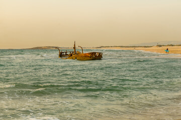 Obraz premium Sunset view of a rusty shipwreck in HaBonim Beach